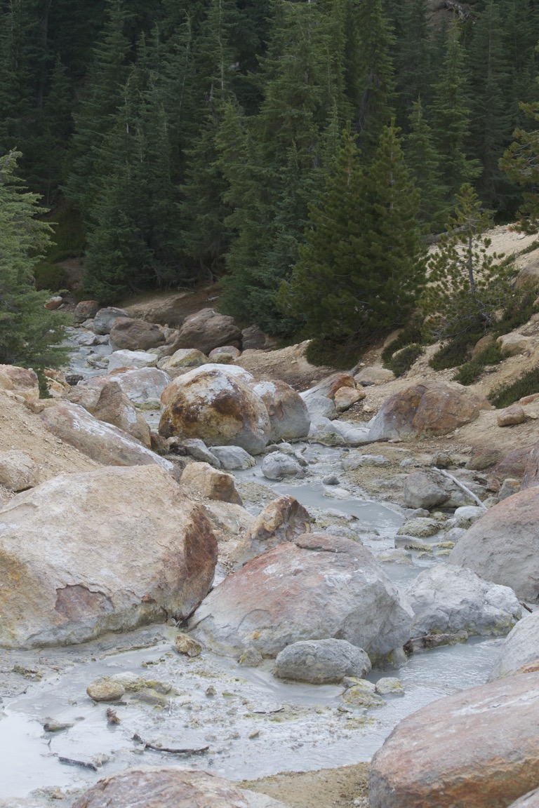 Opaque, gray water trickles between rocks.