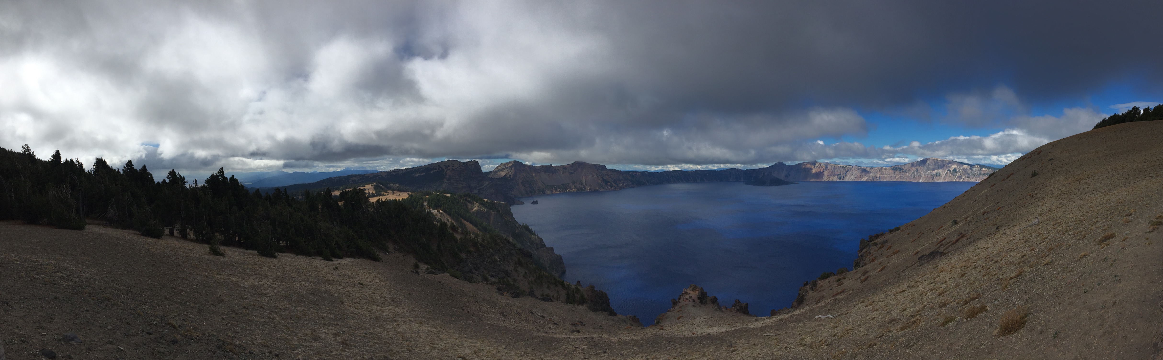 A panorama of the deep-blue Crater Lake and the ominous clouds above.