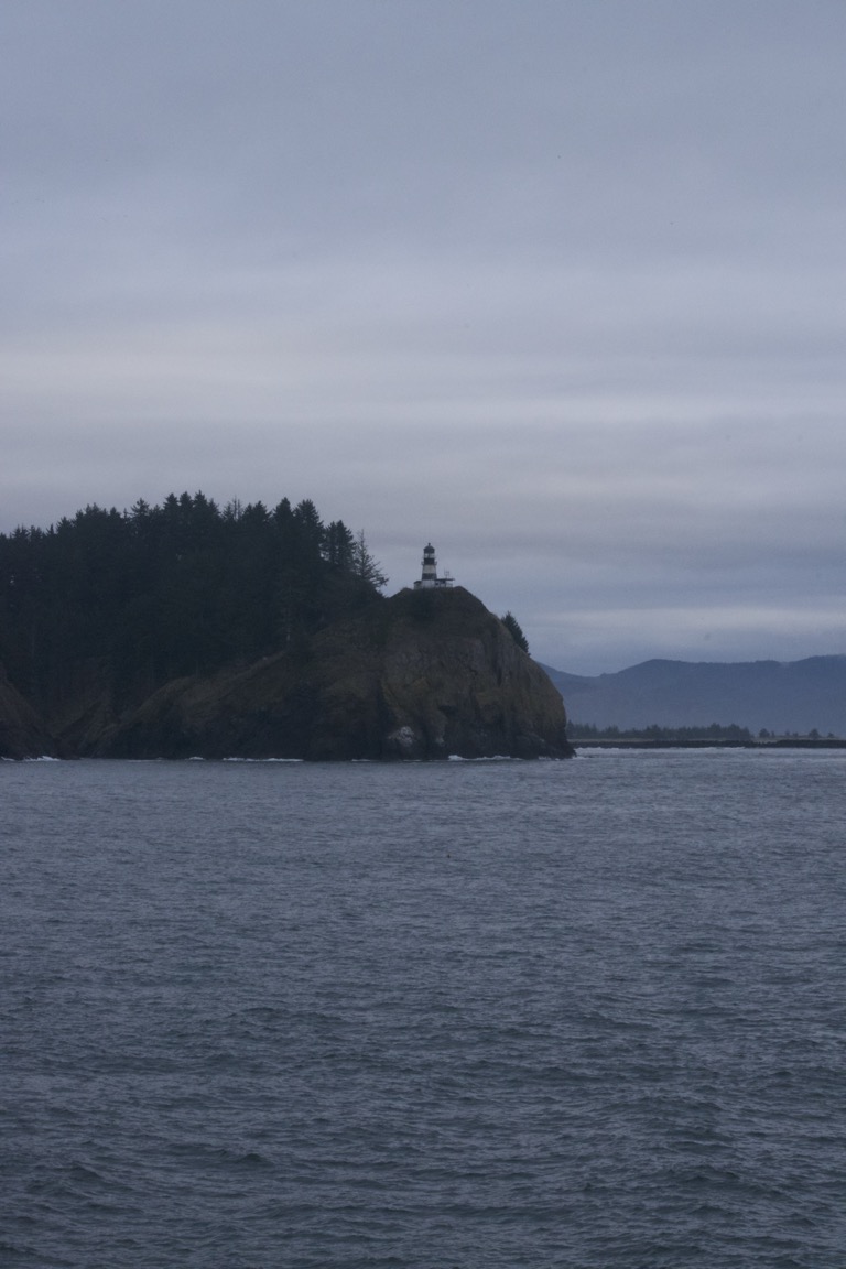 A striped lighthouse sits on a cliff over the water.
